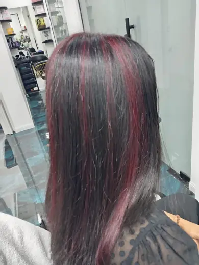Red highlights on dark hair with curled ends at Eternal Beauty Deira