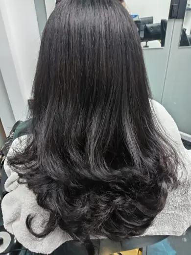 Long healthy black hair styled with soft curled ends at Eternal Beauty